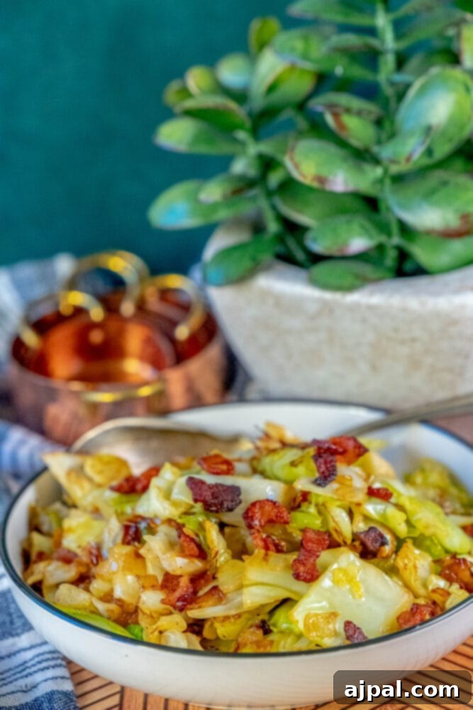 Fried cabbage and bacon in a white bowl, garnished with fresh herbs.