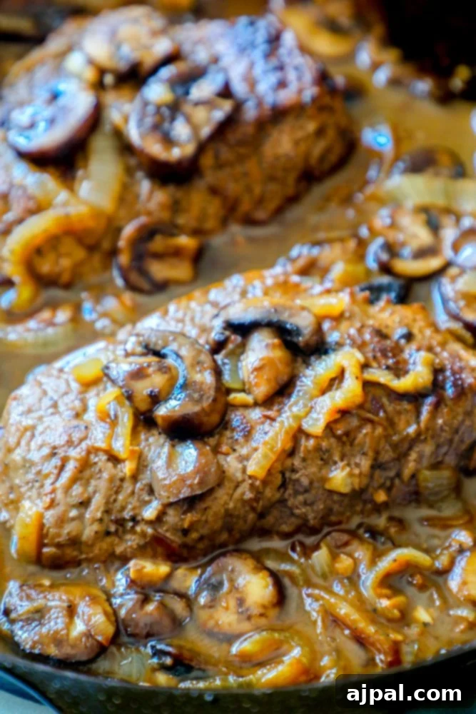Tender Cube Steak Smothered in Savory Gravy 6 A beautifully plated keto cube steak with mushroom and onion gravy, garnished with fresh herbs, showcasing the rich sauce and tender meat.