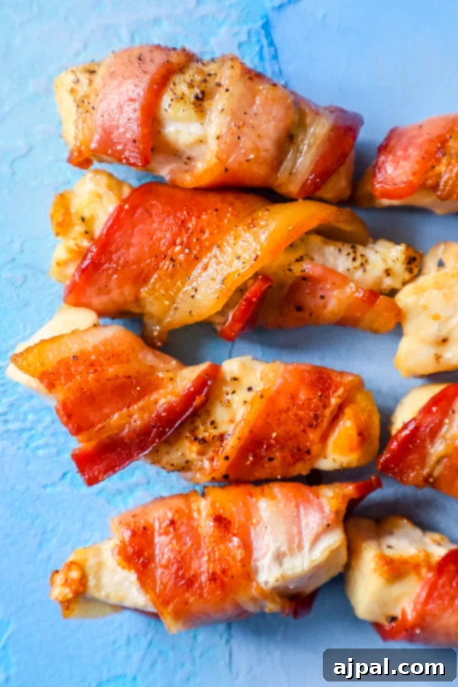 Bacon wrapped chicken skewers on a blue background, perfect for a keto bacon chicken recipe.