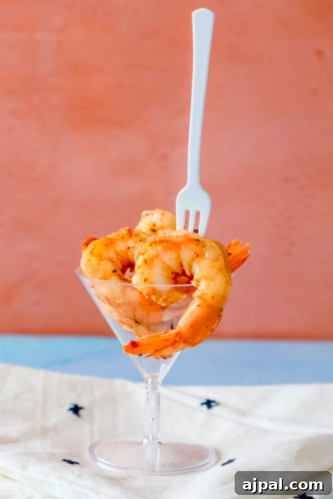 Cajun seasoned shrimp beautifully arranged in a cocktail glass with a fork, ready to be enjoyed.