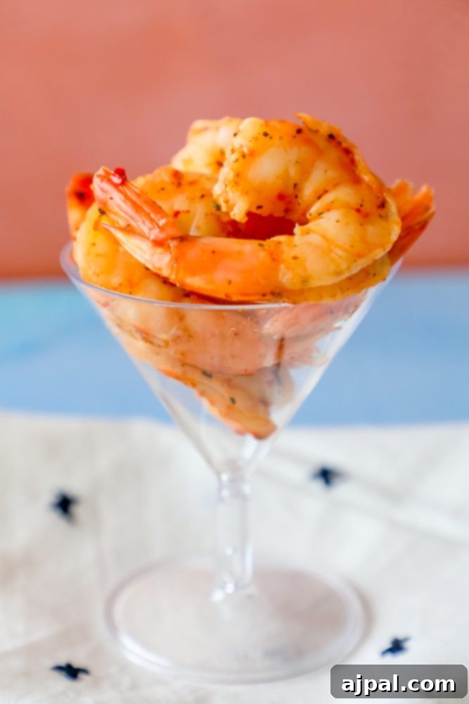 Close-up of buttery Cajun shrimp in a martini glass, seasoned to perfection.