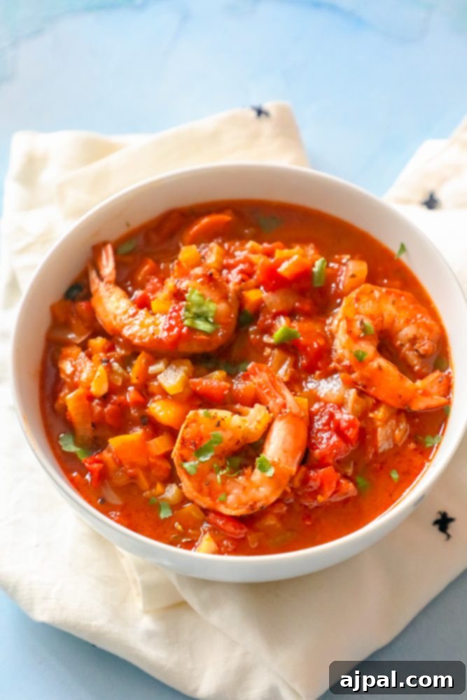 Weeknight One-Pot Creole Shrimp 5 A beautifully presented bowl of shrimp in red Creole sauce, garnished with fresh parsley, sitting on a clean white surface.