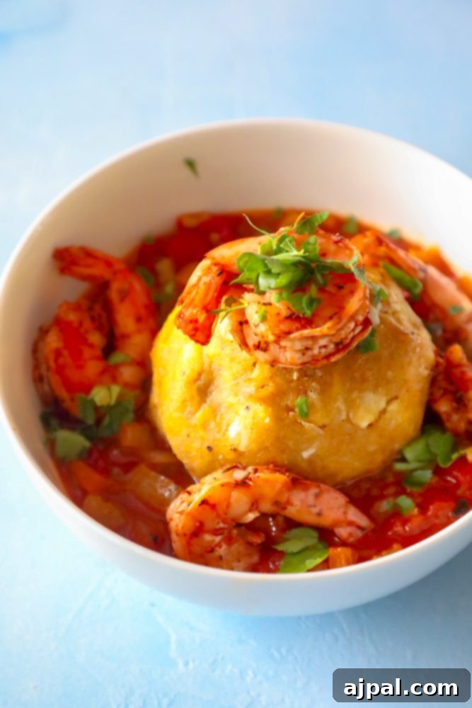 A vibrant Creole shrimp mofongo stew with rice in a rich red sauce, served in a rustic bowl.