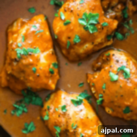 Keto Butter Chicken breasts in a skillet with sauce and parsley.