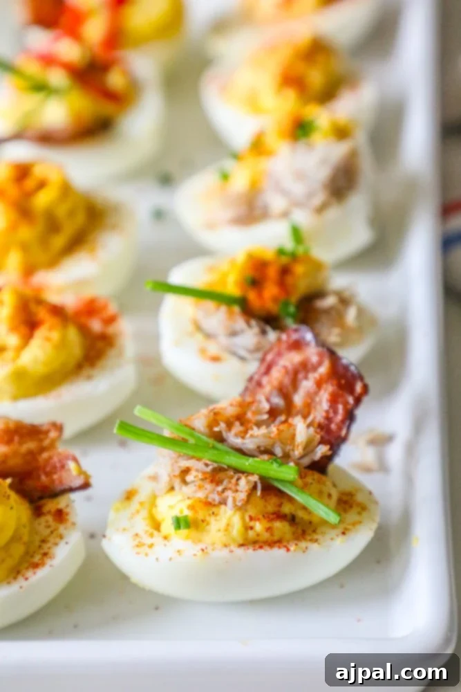 Crab and Bacon Deviled Eggs 4 A platter of elegant deviled eggs, each topped with a generous sprinkle of chives, rich crab meat, and crispy bacon, arranged appealingly on a white plate.