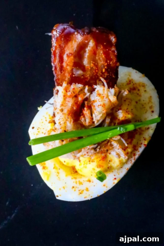 Crab and Bacon Deviled Eggs 5 A single, perfectly crafted deviled egg, adorned with fresh chives, rich crab meat, and crispy bacon, ready to be enjoyed.
