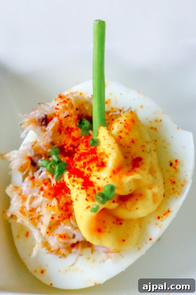 Spicy Crab Bloody Mary Deviled Eggs 2 Exquisite deviled egg halves, adorned with a creamy, spicy Bloody Mary-infused yolk filling, succulent crab meat, and a sprinkle of fresh green onions, presented beautifully on a platter.