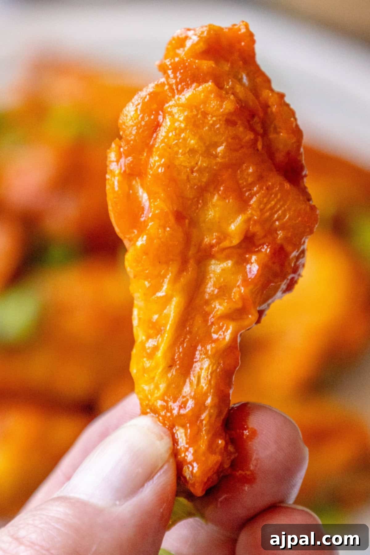 A serving of perfectly baked chicken wings, glistening with sauce, resting on a white platter, inviting diners to enjoy their crispy texture and savory flavor.