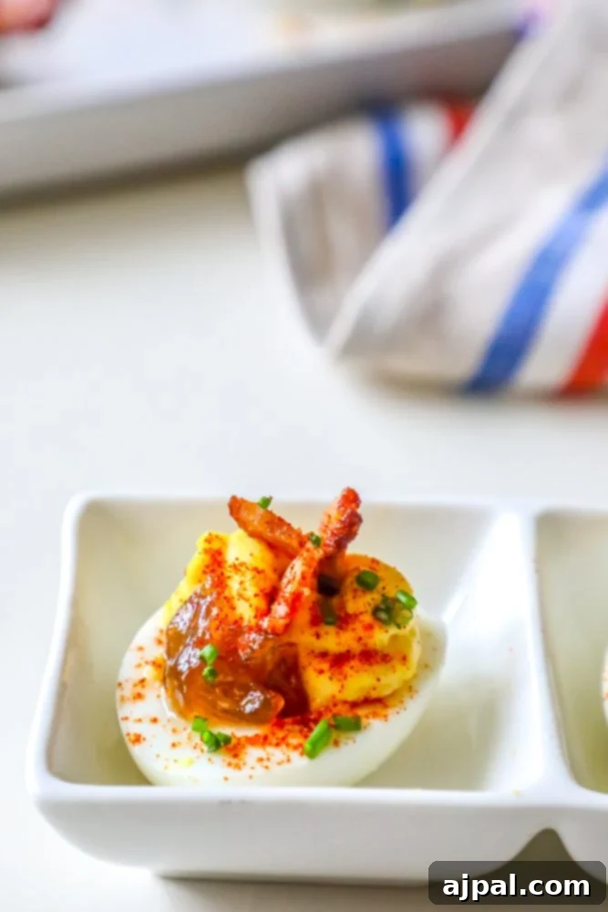 Deviled Delights with Bacon Onion Jam 2 Gourmet deviled eggs topped with rich bacon and onion jam, fresh chives, and a sprinkle of paprika, ready to serve.