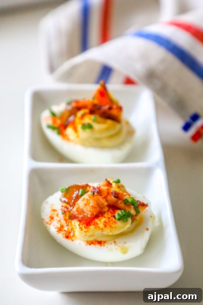 Deviled Delights with Bacon Onion Jam 4 A close-up of gourmet deviled eggs, showcasing the creamy filling, crisp bacon, sweet onion jam, and fresh chives, artfully arranged on a serving plate.