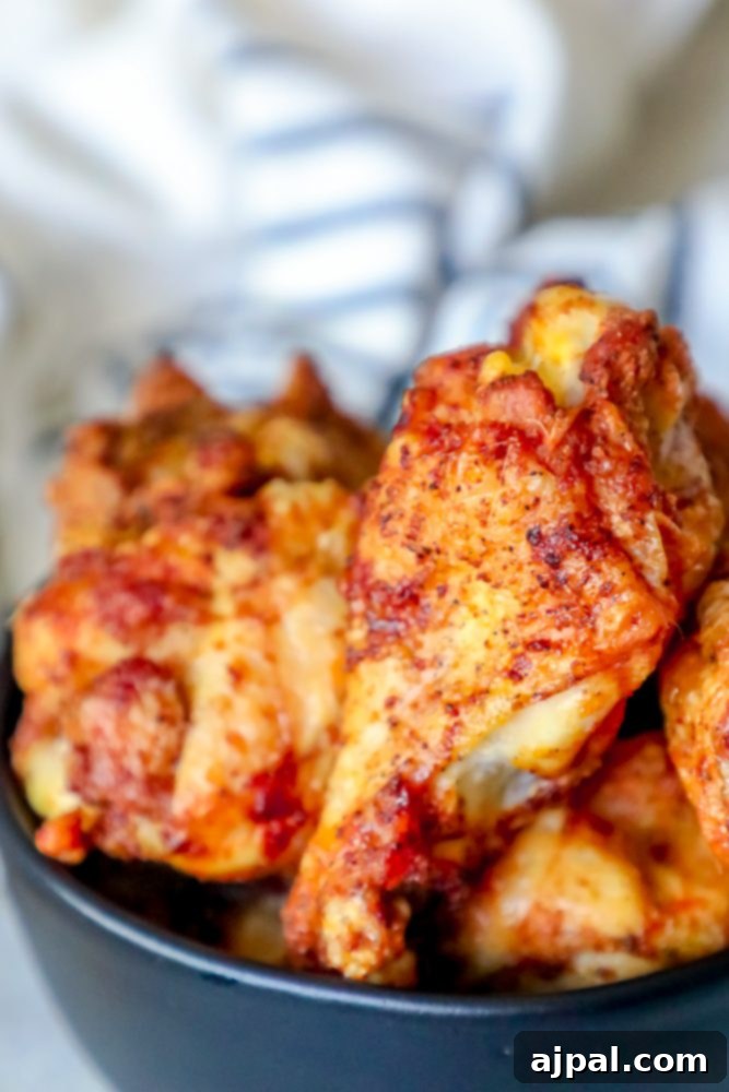 Spicy Cajun Baked Chicken Wings 7 Baked chicken wings piled together in a black bowl, garnished with fresh herbs.