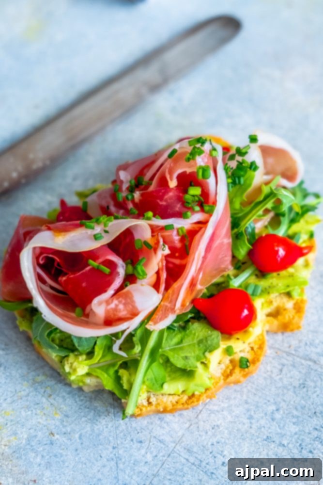 The Best Easy Keto Avocado Toast Recipe, featuring avocado, ham, and tomatoes on a low-carb bread slice.