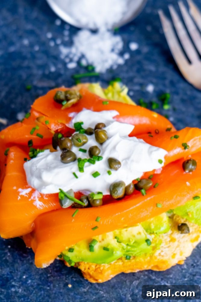 A vibrant keto avocado toast generously topped with smoked salmon and capers.