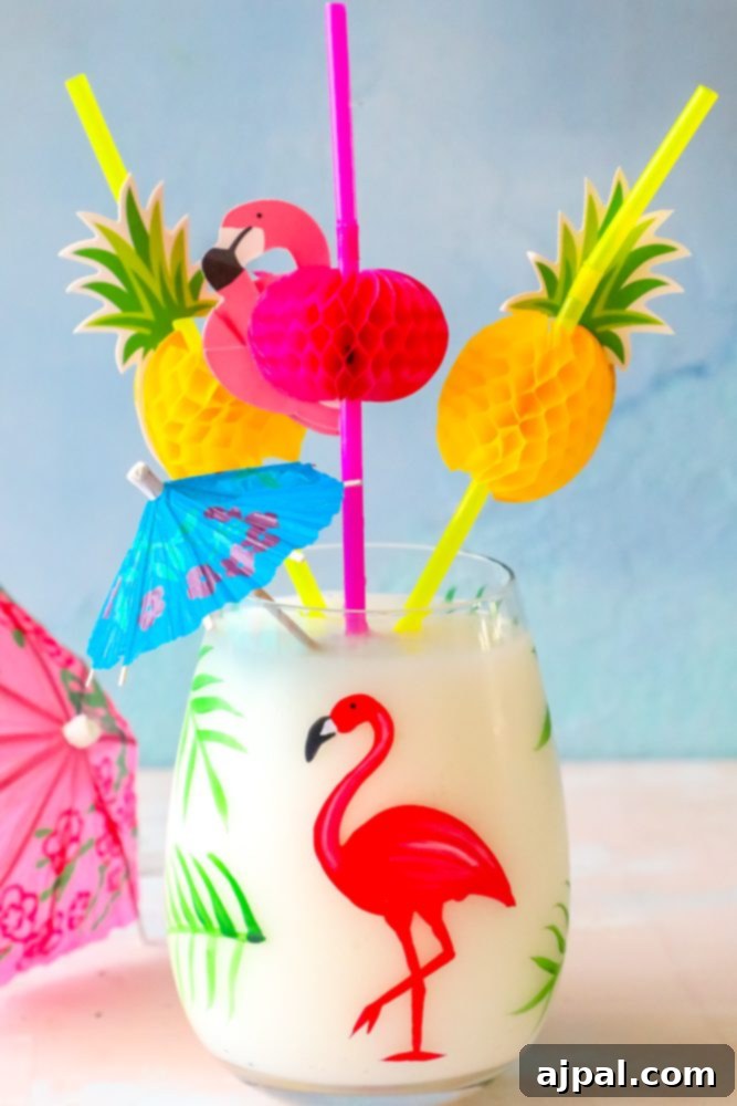 A vibrant tropical Pina Colada, artfully garnished with a tiny flamingo stir stick and a classic paper umbrella, set against a blurred tropical background.