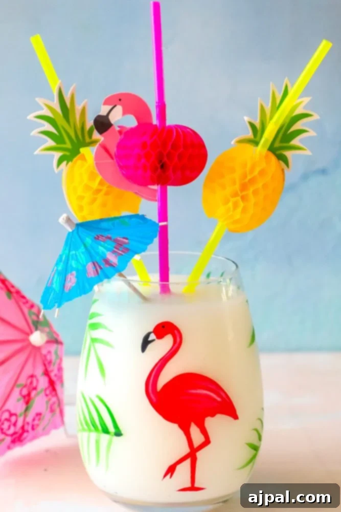 A vibrant tropical Pina Colada, artfully garnished with a tiny flamingo stir stick and a classic paper umbrella, set against a blurred tropical background.