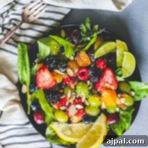 A bowl of fruit salad with almonds, lemons, and spinach.