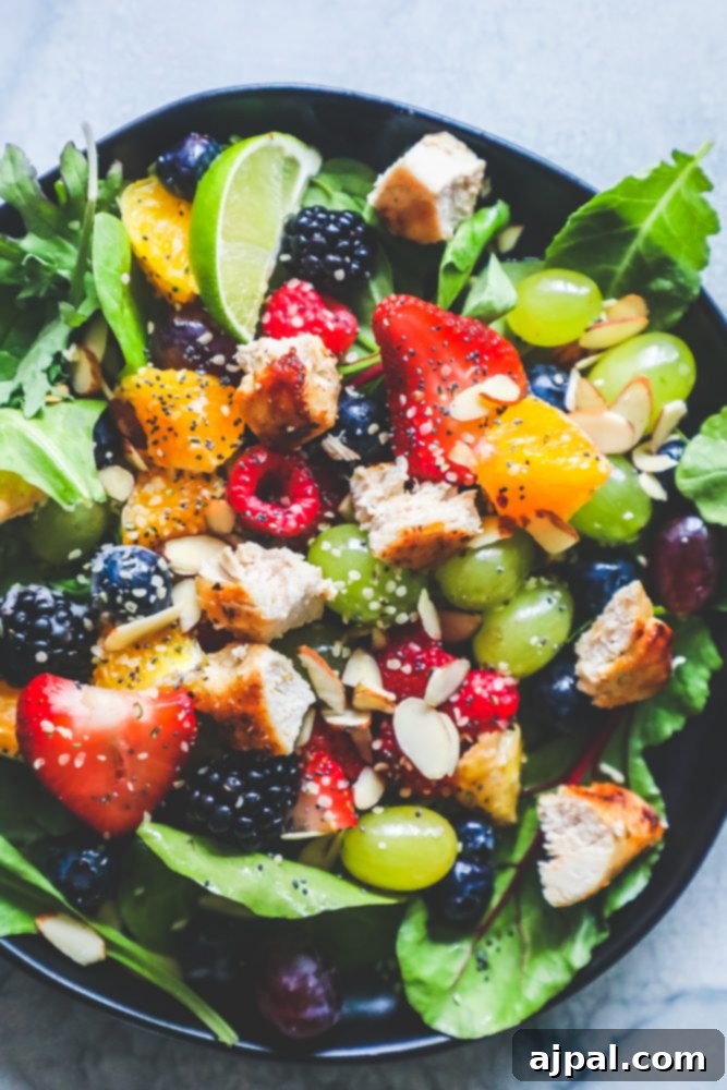 A vibrant and refreshing Chicken and Fruit Salad with Poppyseed Dressing, presented beautifully on a black plate, showcasing tender chicken, fresh berries, and a tangy dressing.
