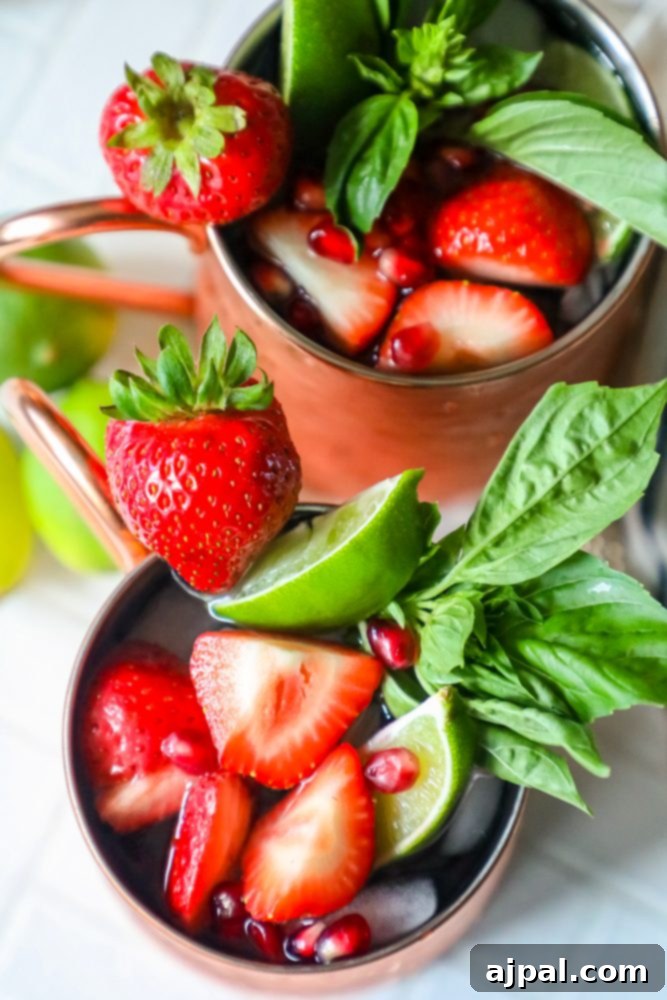 Fresh Strawberry Basil Moscow Mule 2 Picture of a Strawberry Basil Moscow Mule in a copper cup, garnished with fresh strawberries, mint, basil, and ice.