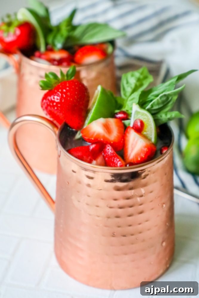 Fresh Strawberry Basil Moscow Mule 4 Picture of a Moscow Mule in a copper cup, garnished with strawberries, mint, basil, and ice, highlighting the refreshing blend.