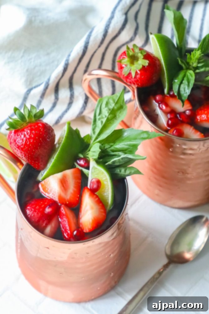 Fresh Strawberry Basil Moscow Mule 5 Picture of two Moscow Mule copper mugs filled with strawberries and mint, ready to be served.