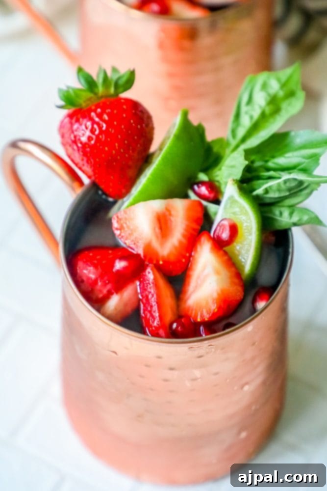 Fresh Strawberry Basil Moscow Mule 7 Picture of a Moscow Mule in a copper cup, garnished with strawberries and mint, showcasing a berry-infused variation.
