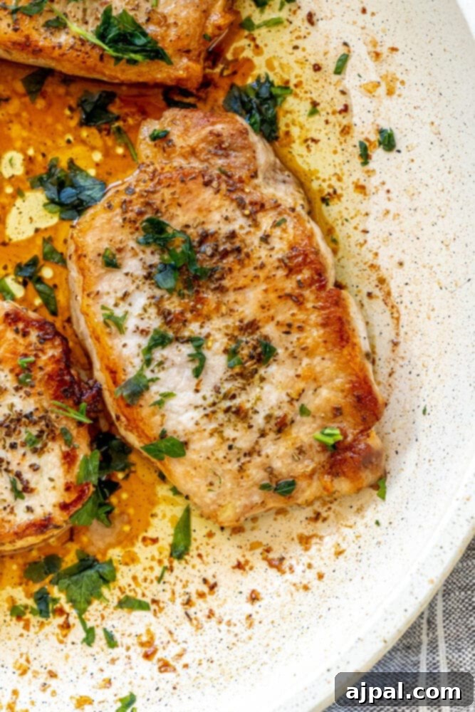 Perfectly Pan Fried Thin Pork Chops 10 A freshly pan-fried pork chop, golden brown and perfectly seared, resting elegantly in a hot skillet, ready to be served.