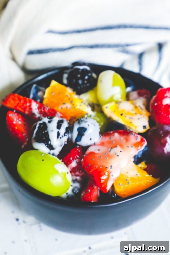 A rich, dark bowl brimming with an assortment of fresh berries and citrus segments, all glistening under a generous coating of lemon poppyseed glaze.