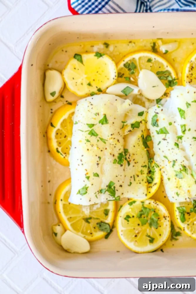 Lemony Garlic Baked Cod 2 picture of baked cod in a ceramic dish with lemon slices and garlic cloves in the dish