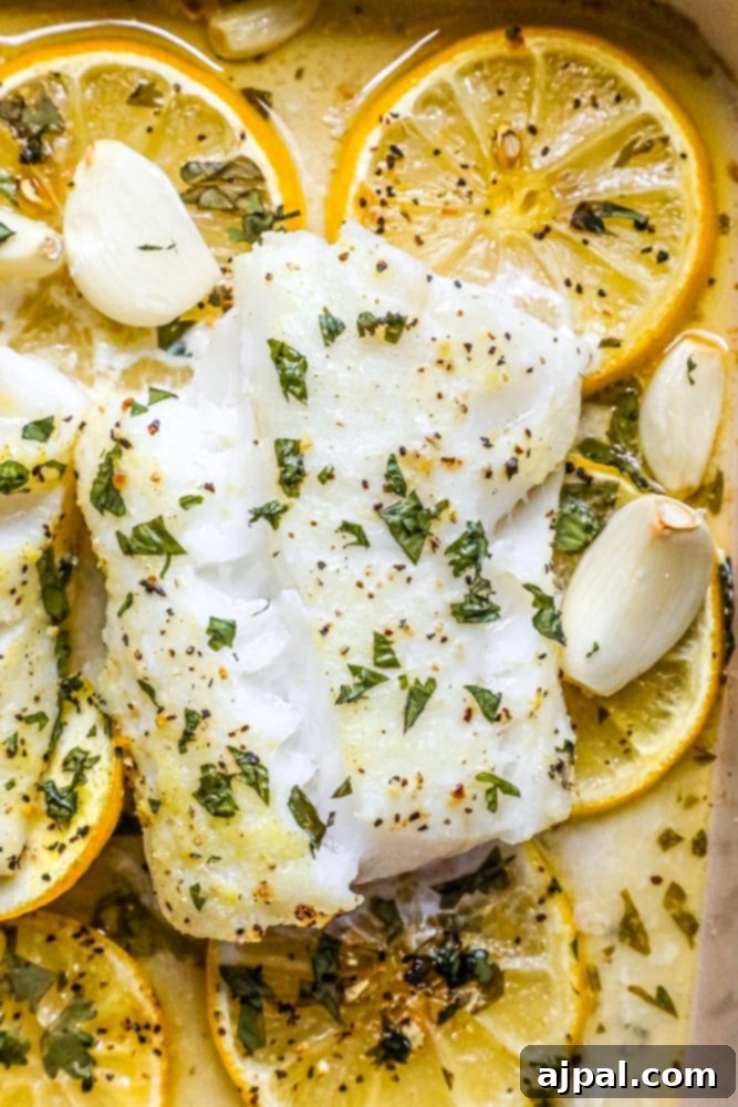 Lemony Garlic Baked Cod 8 picture of baked cod in a ceramic dish with lemon slices and garlic cloves in the dish