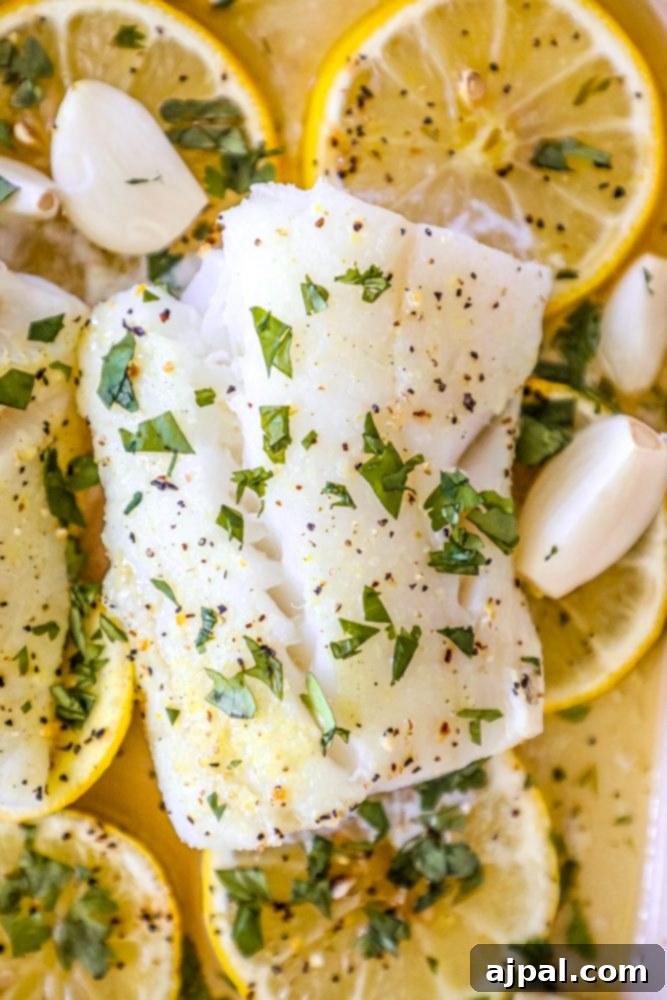 Lemony Garlic Baked Cod 3 picture of baked cod in a ceramic dish with lemon slices and garlic cloves in the dish