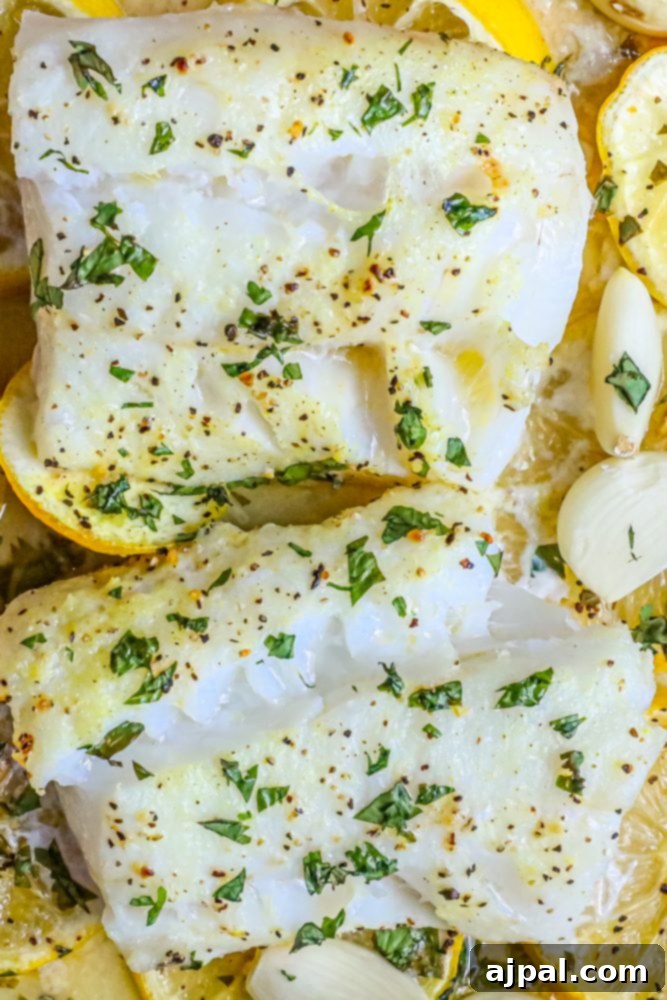 Lemony Garlic Baked Cod 5 picture of baked cod in a ceramic dish with lemon slices and garlic cloves in the dish