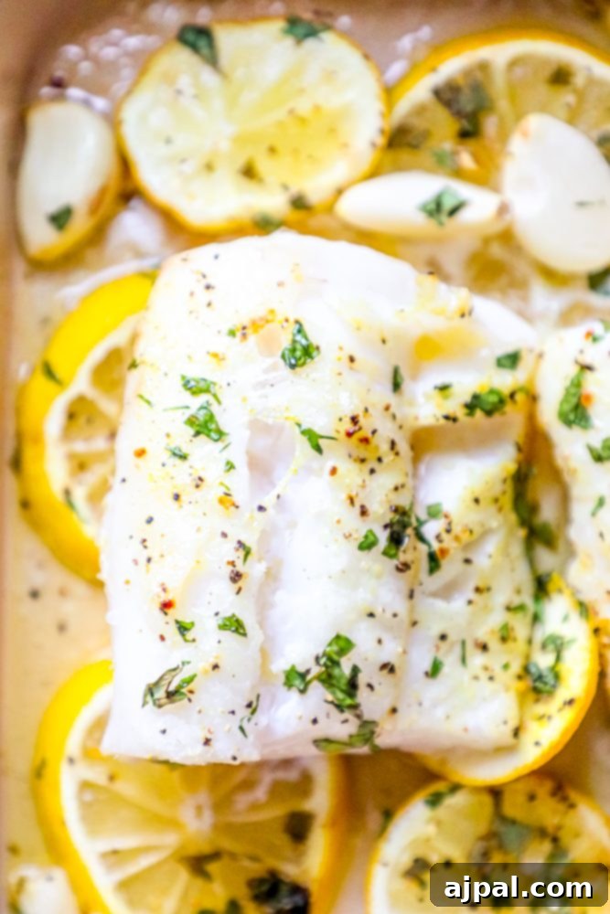 Lemony Garlic Baked Cod 6 picture of baked cod in a ceramic dish with lemon slices and garlic cloves in the dish