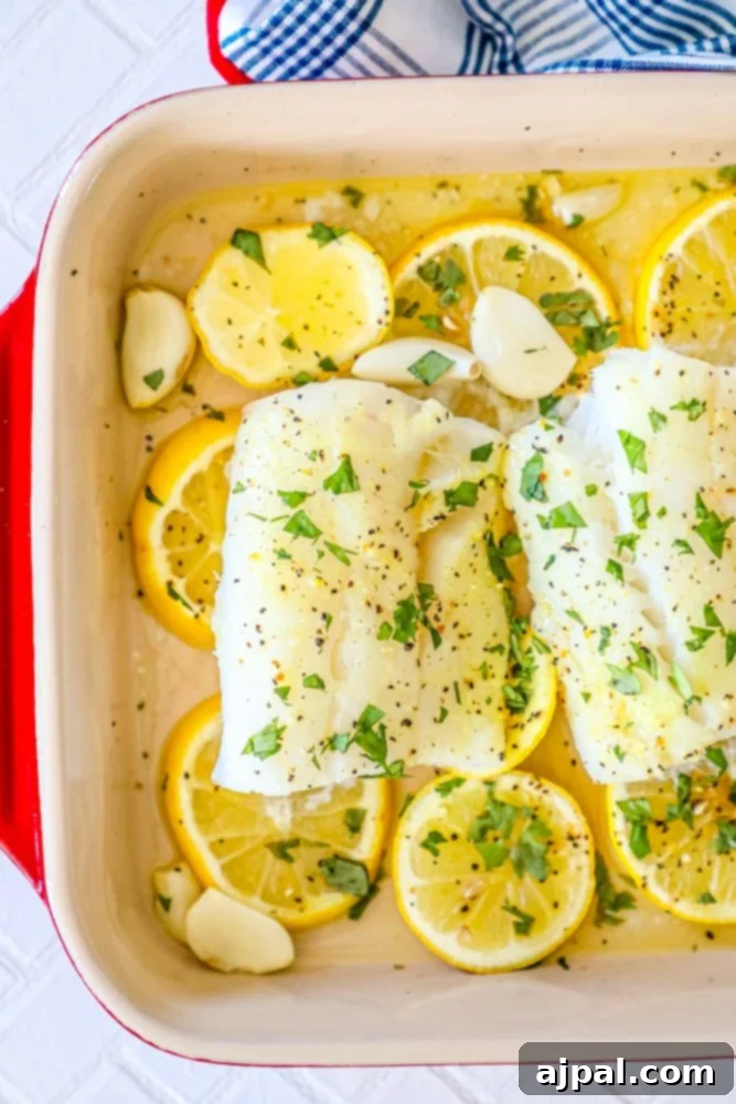 Lemony Garlic Baked Cod 7 picture of baked cod in a ceramic dish with lemon slices and garlic cloves in the dish