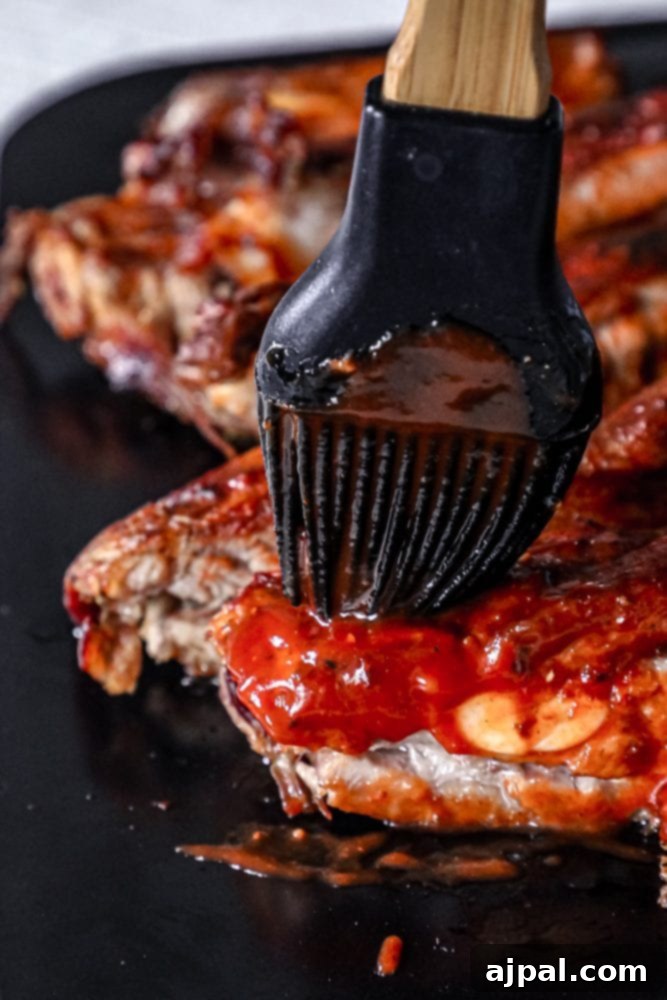 A brush applying rich barbecue sauce to slow cooker ribs, enhancing their flavor and appearance.