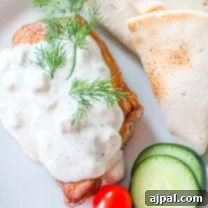 A plate with chicken, tomatoes, and cucumbers served with a creamy feta sauce.