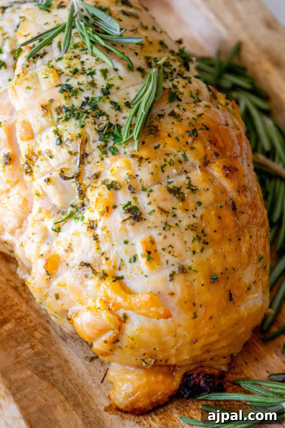 Perfectly Juicy Oven Roasted Turkey Breast 6 A roasted turkey on a cutting board with sprigs of rosemary. Oven Baked Turkey Breast.