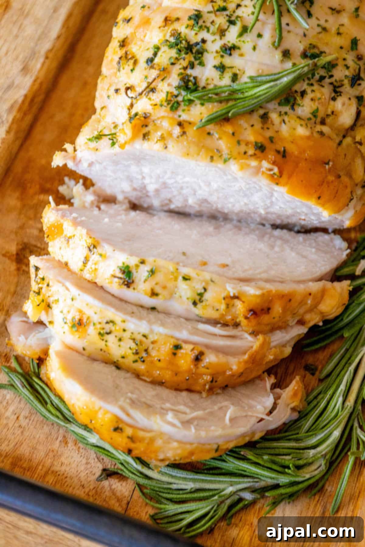 Perfectly Juicy Oven Roasted Turkey Breast 3 Sliced turkey with rosemary on a cutting board, showcasing an easy and delicious turkey breast recipe.