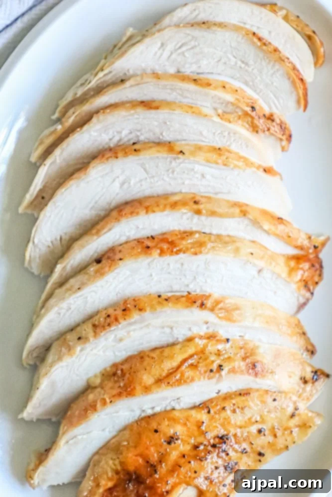 Perfect Instant Pot Turkey Breast 5 A close-up of beautifully sliced, juicy turkey breast in front of an Instant Pot, presented on a pristine white plate, garnished with fresh herbs.
