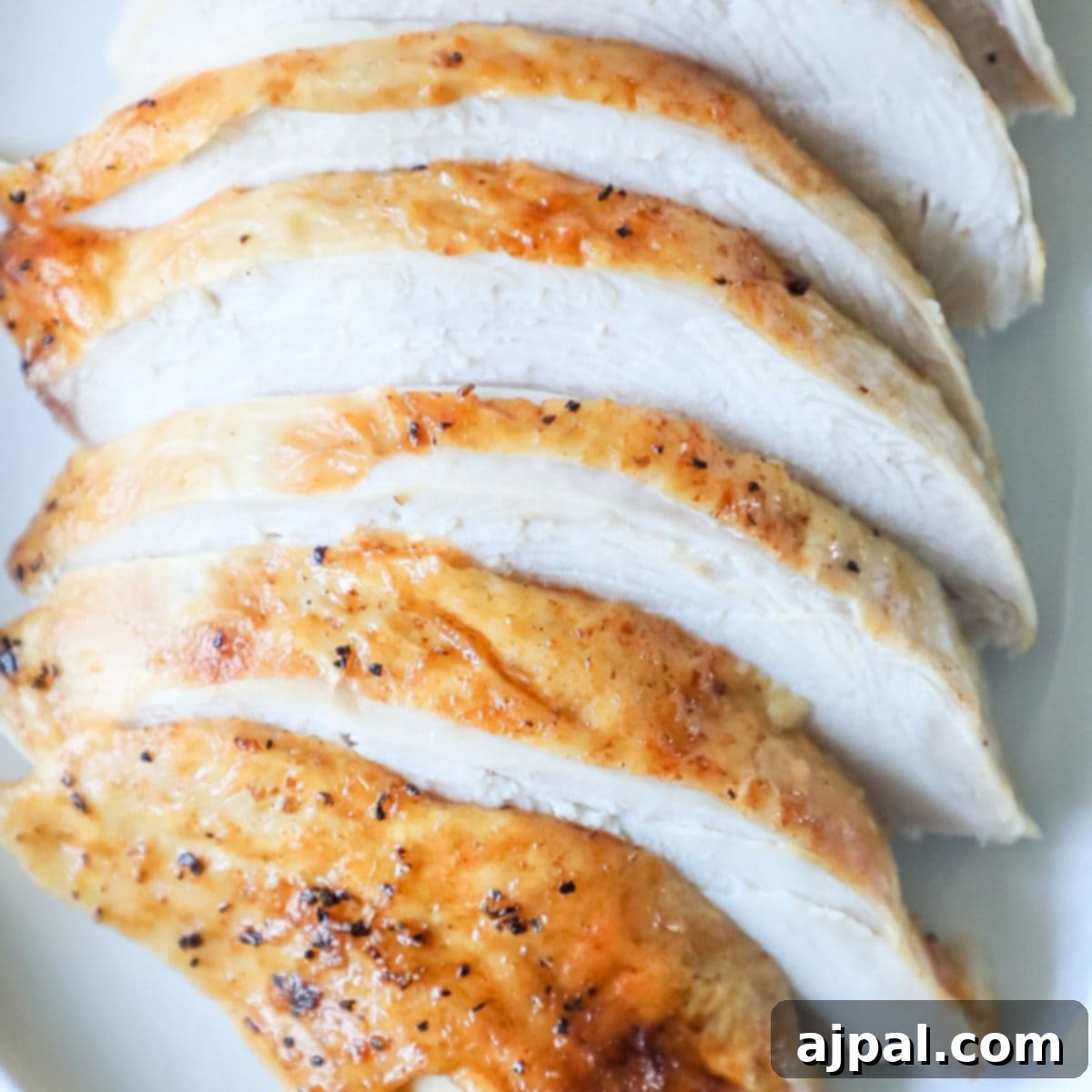 Perfect Instant Pot Turkey Breast 8 Beautifully sliced chicken breasts arranged neatly on a white plate, showcasing a perfectly oven-baked texture.