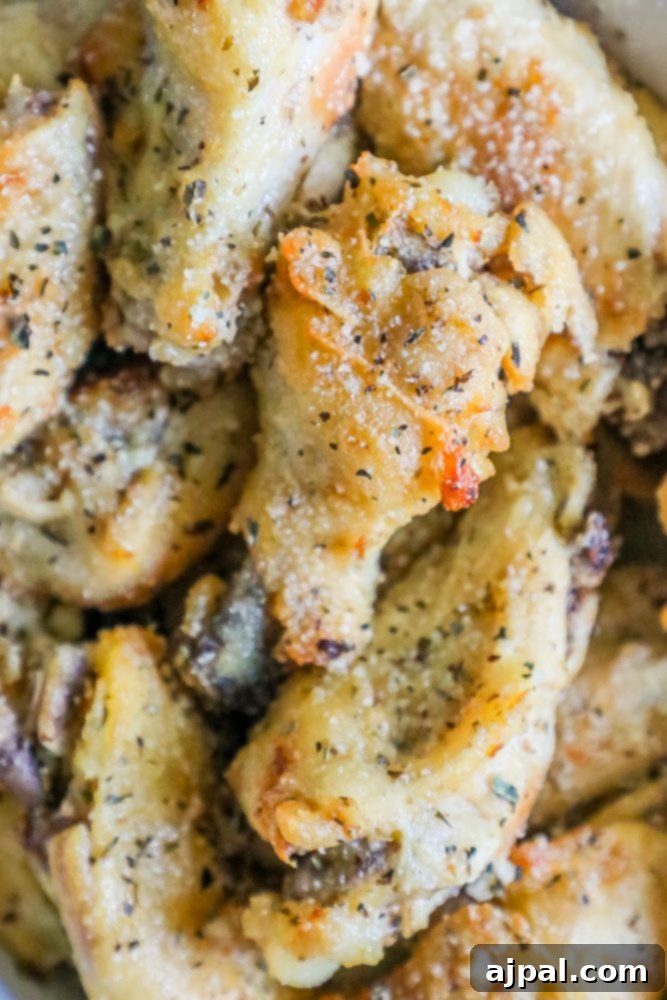 A large white bowl brimming with slow cooker garlic butter parmesan chicken wings, ready to be served.