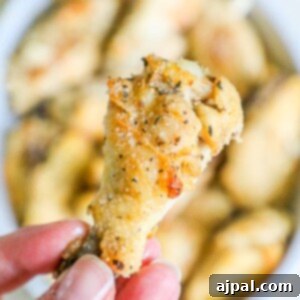 A person holding a small piece of Slow Cooker Garlic Parmesan Chicken Wings.