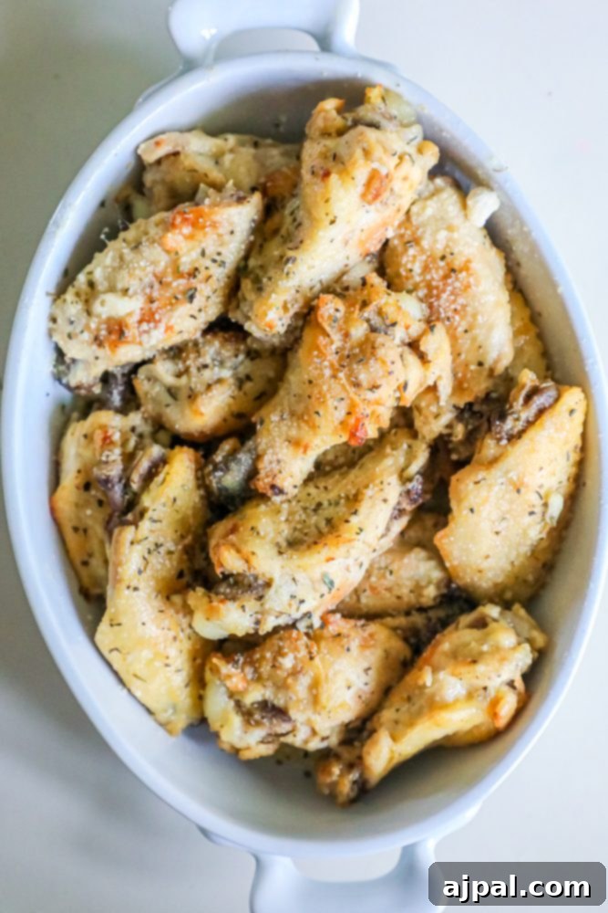 A serving of Slow Cooker Garlic Parmesan Chicken Wings arranged neatly in a white bowl, garnished with fresh herbs, ready to be enjoyed.