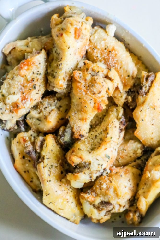 Close-up of garlic parmesan chicken wings served in a white bowl, glistening with sauce and ready to be served.