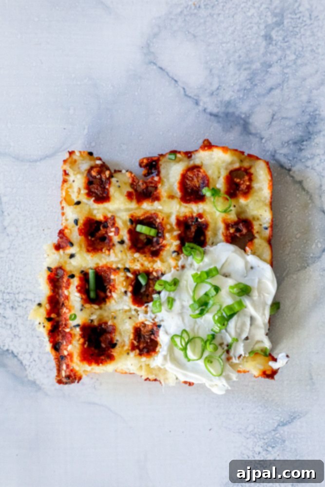 Ultimate Keto Chaffles 2 Crispy keto chaffle waffles on a countertop, ready to be served, with a side of sour cream and fresh green onions
