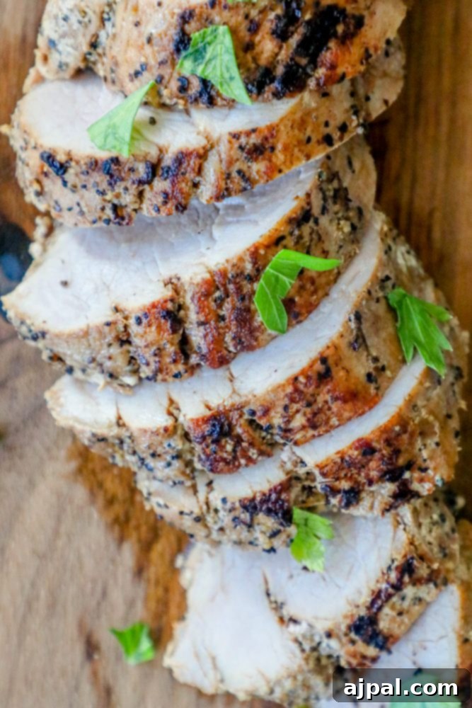 Ultimate Pressure Cooker Pork Tenderloin 2 Sliced pork tenderloin medallions on a wooden cutting board, garnished with fresh herbs.