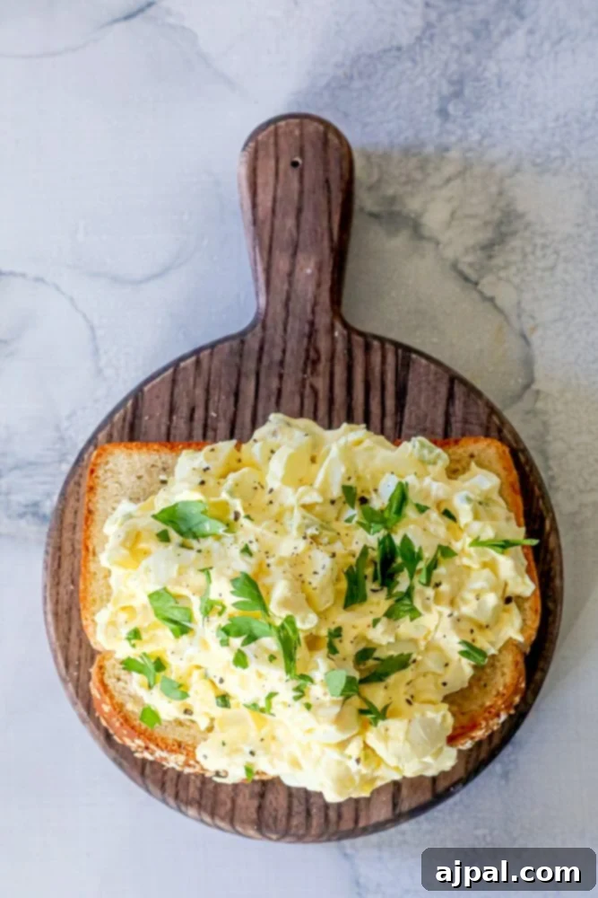 A beautifully presented classic egg salad on a rustic wooden cutting board, ready to be served.