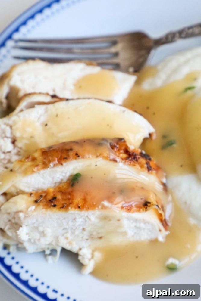 turkey covered in gravy with a fork behind it.