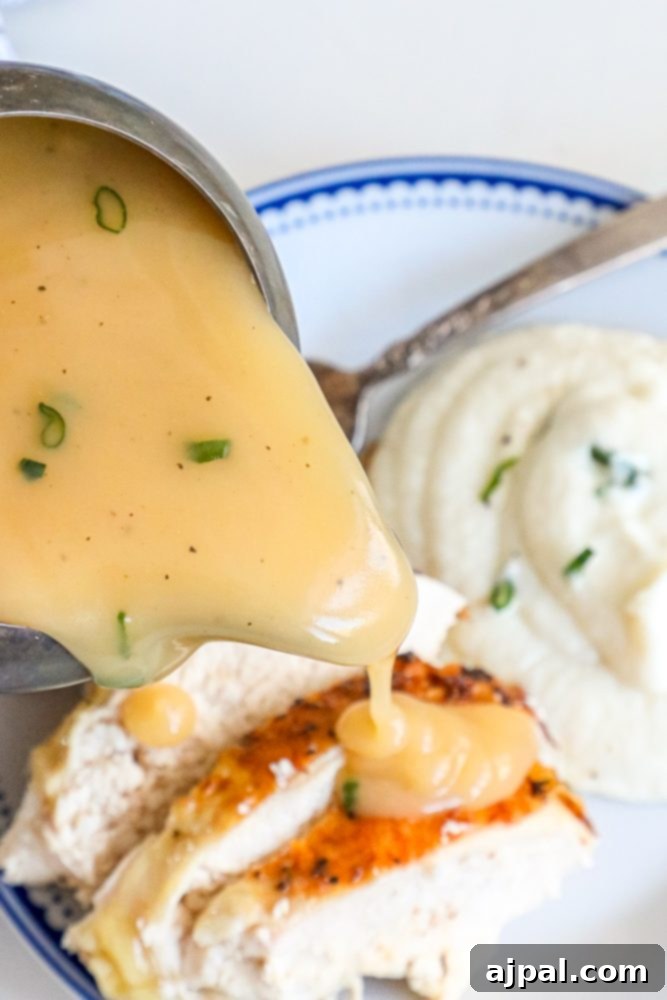 gravy being poured over turkey and mashed potatoes on a white and blue plate.