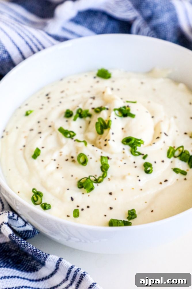 A bowl of creamy mashed cauliflower garnished with fresh chives.