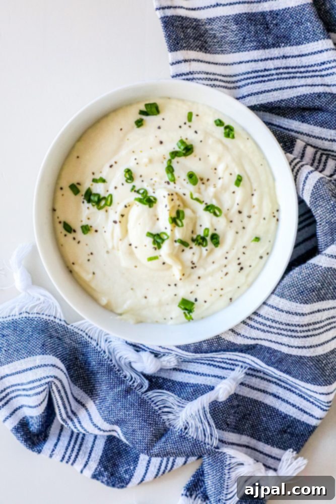 A bowl of mashed cauliflower resting on a blue and white patterned towel, ready to be served.